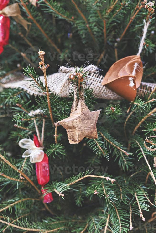 estrella de madera vintage y juguete de cuero en el árbol de navidad. adornos naturales de bricolaje para el árbol de navidad, cero desperdicio de navidad foto