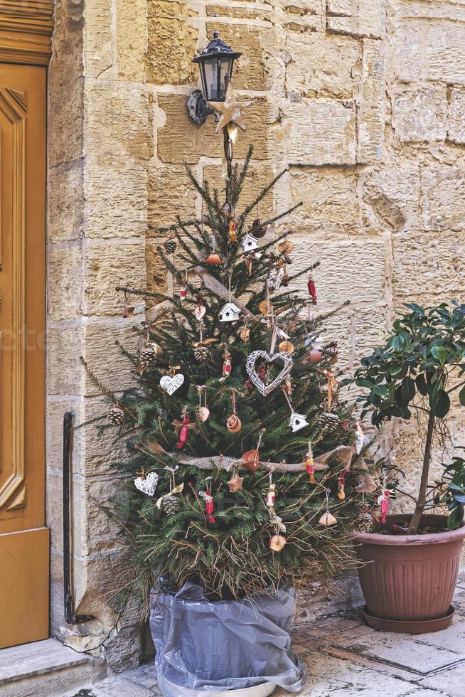 árbol de navidad decorado con una corona tejida en forma de corazón y otros adornos navideños hechos a mano sin desperdicio foto