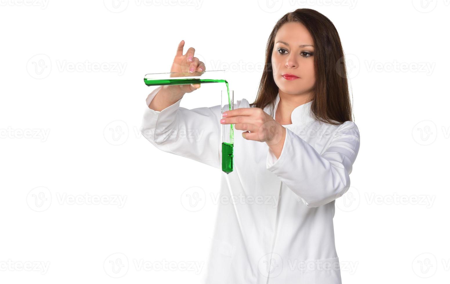 científica femenina sosteniendo dos tubos transfiriendo líquido verde de uno a otro. aislado sobre fondo blanco. foto