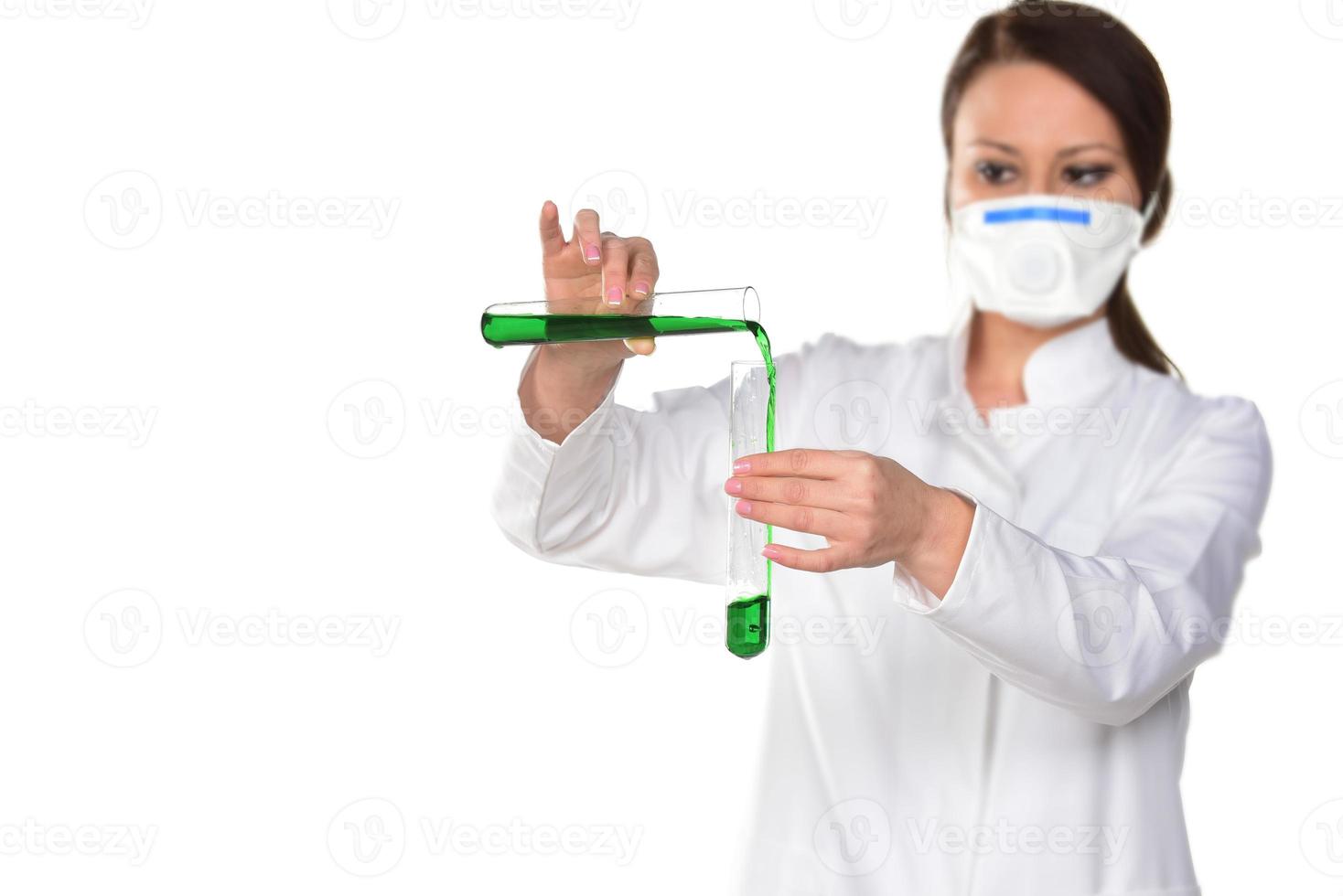 Female scientist holding two tubes transferring green liquid from one to another. Isolated on white background. photo