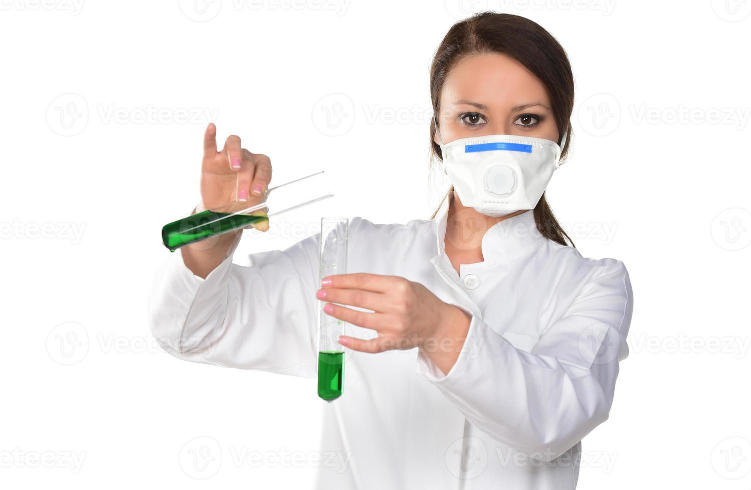 Female scientist holding two tubes transferring green liquid from one to another. Isolated on white background. photo