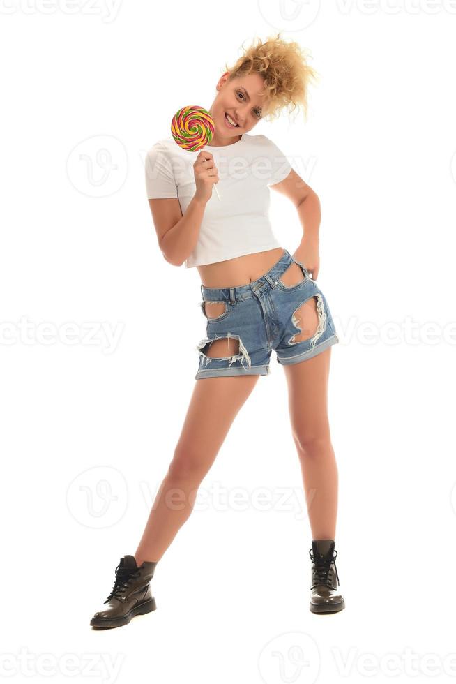 Blonde woman licking sweet candy. Female model eating delicious confectionery lollipop with surprised expression. studio shot isolated white background, photo