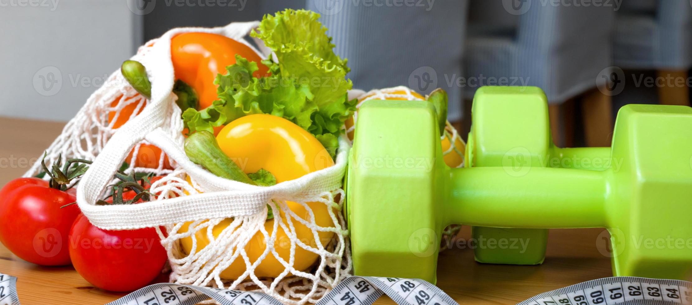 Healthy diet concpet. Vegetables in string bag near mesuring tape. Vegetarian,vegan.Sport lifestyle. Dumbbells photo