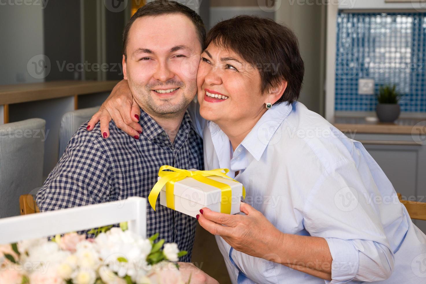 feliz madre con regalo abraza a su hijo. concepto del día de la madre o del 8 de marzo foto