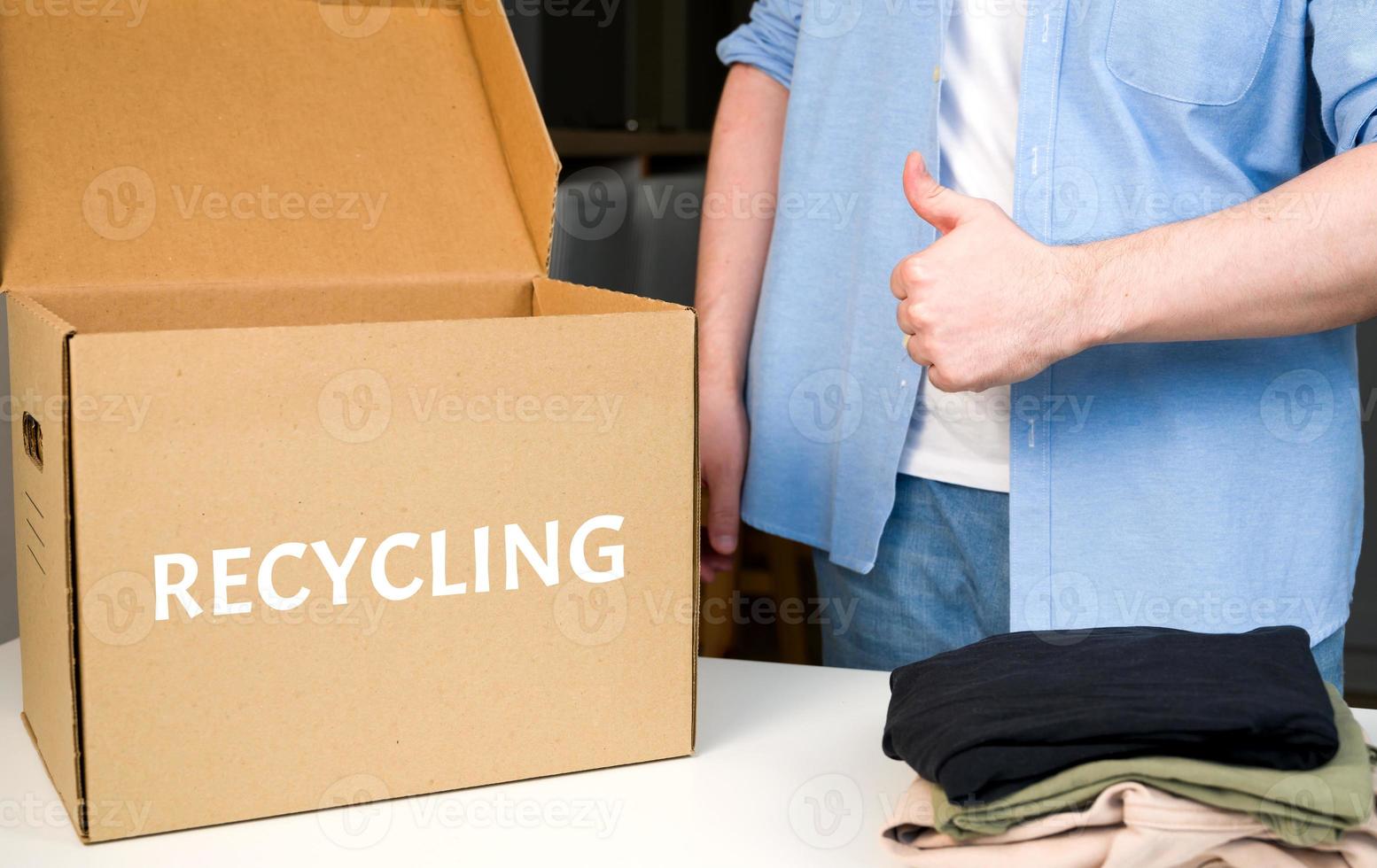 reciclar el concepto de ropa. caja de reciclaje con ropa. vida sostenible.hombre mostrando que reciclar es bueno foto