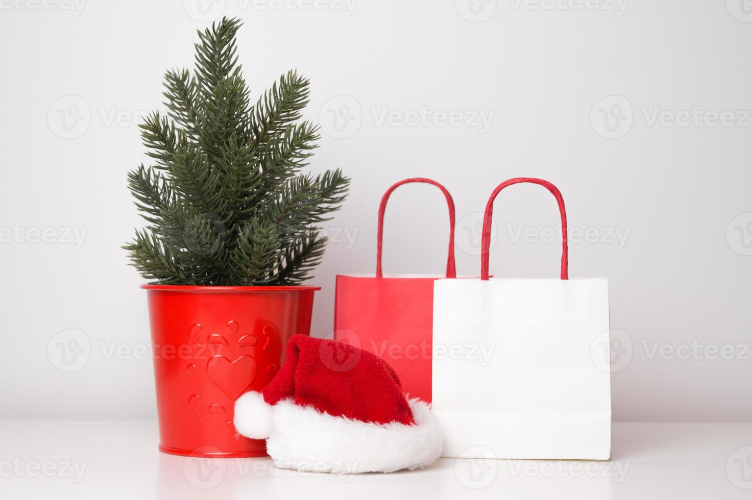 Christmas, new year sale or shopping concept. Paper bags near christmas tree and santa hat photo