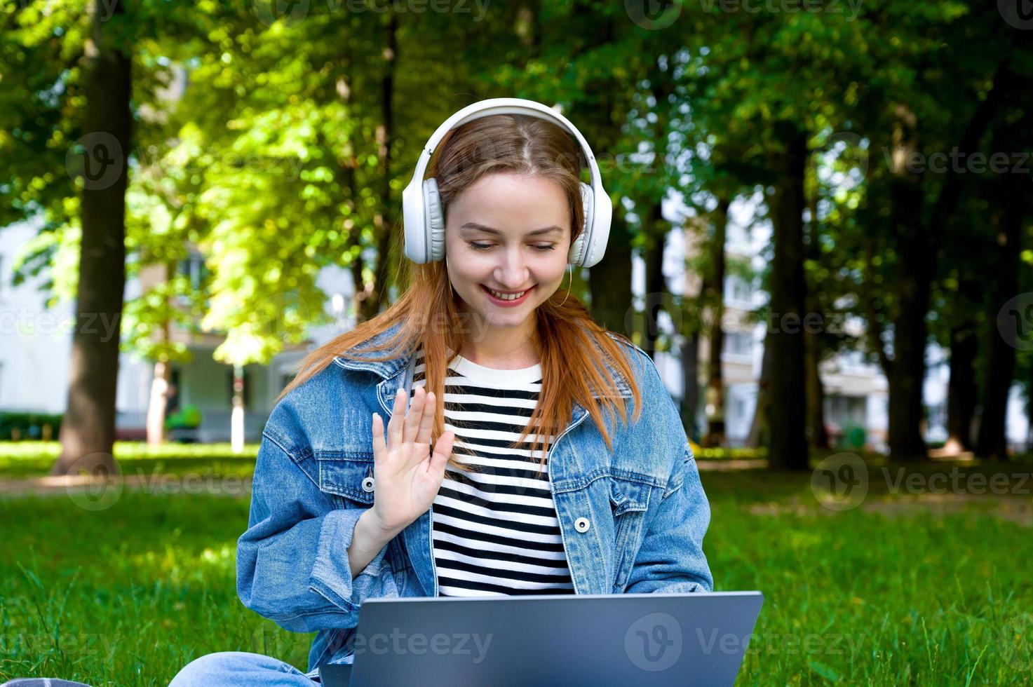 Young happy red haired firl in headphone communication over internet. Work call or online study group. remote work or e-learning photo