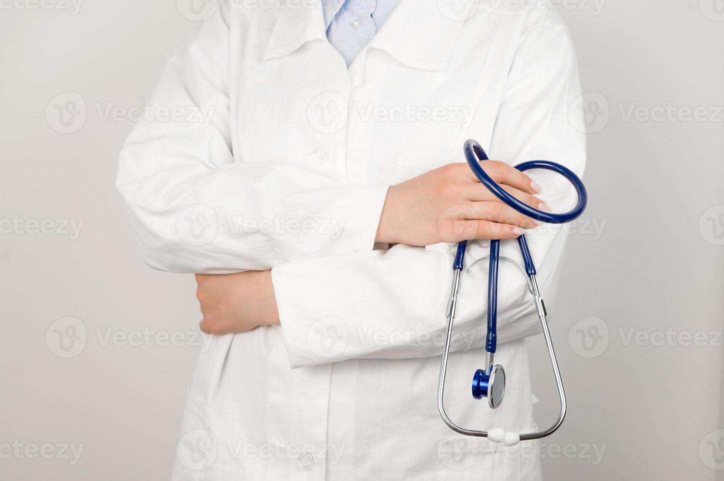 A doctor in a white medical coat holds a stethoscope in his hands. Healthcare concept. photo