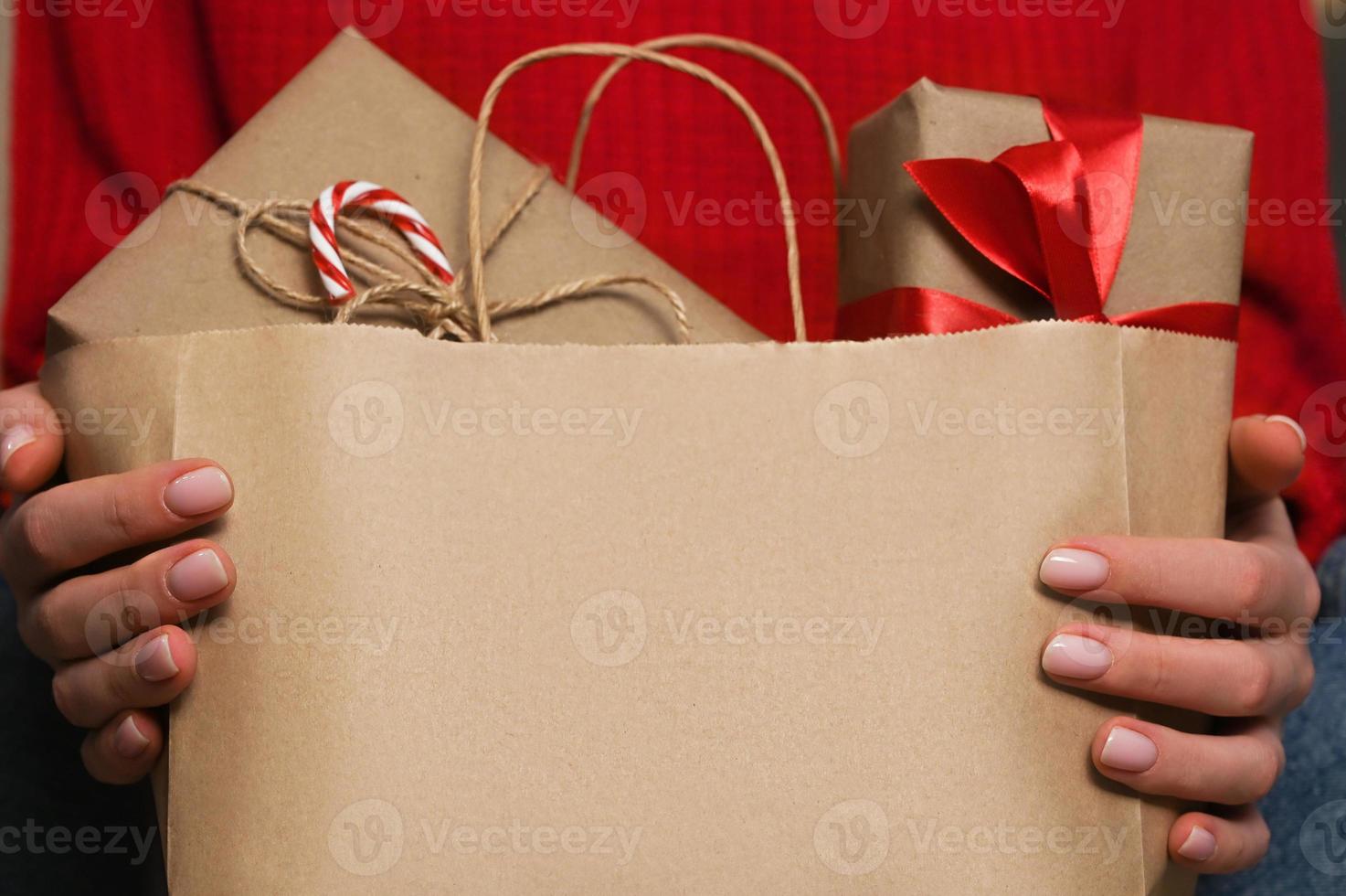 primer plano de una mujer irreconocible que sostiene una bolsa de artesanía con regalos de navidad envueltos. concepto de compras. vale la pena copyspace.delivery foto