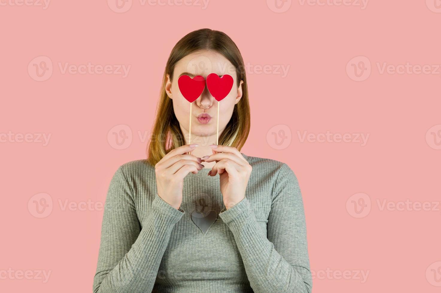 Blonde female with hearts against pink background. St Valentine's studio portrait photo