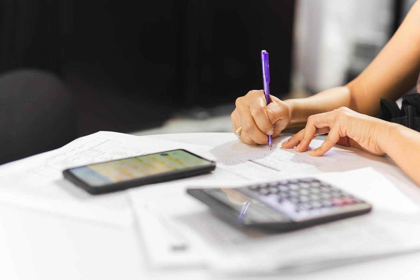 Businesswoman signing document signature agreement with cell phone  on table. photo