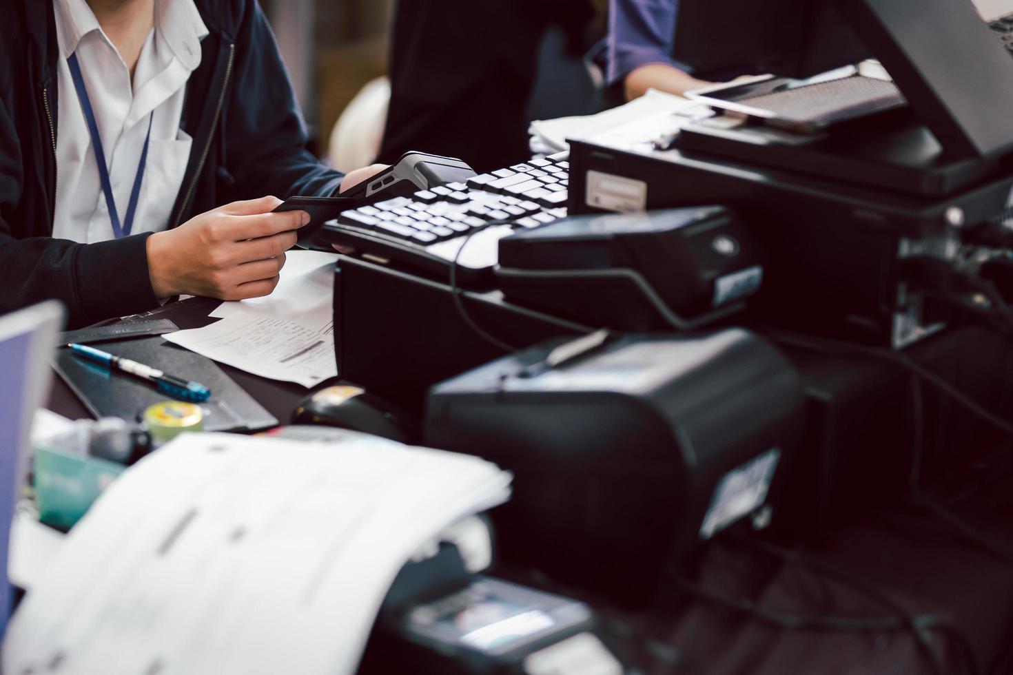 Employee holding customers credit card to pay for service via electronic card swipe machine. photo