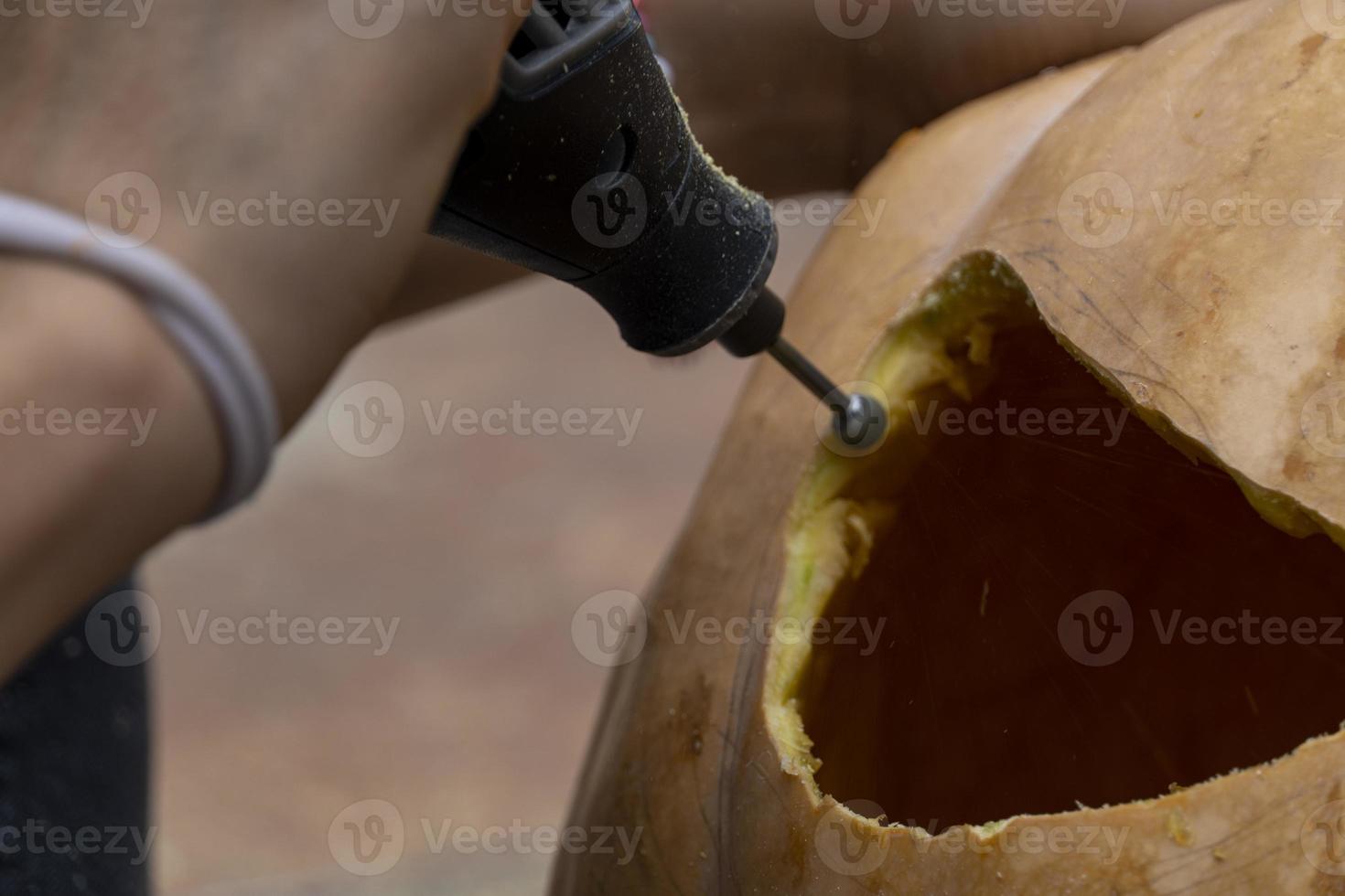 young man with a drill or dremel drilling a pumpkin for halloween photo