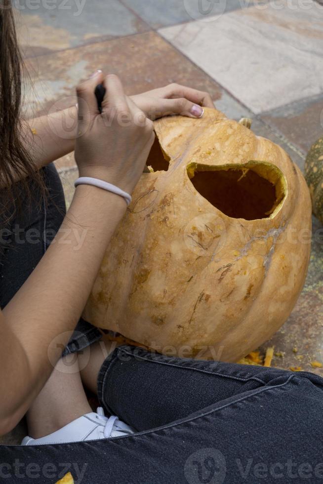joven con un taladro o dremel perforando una calabaza para halloween foto