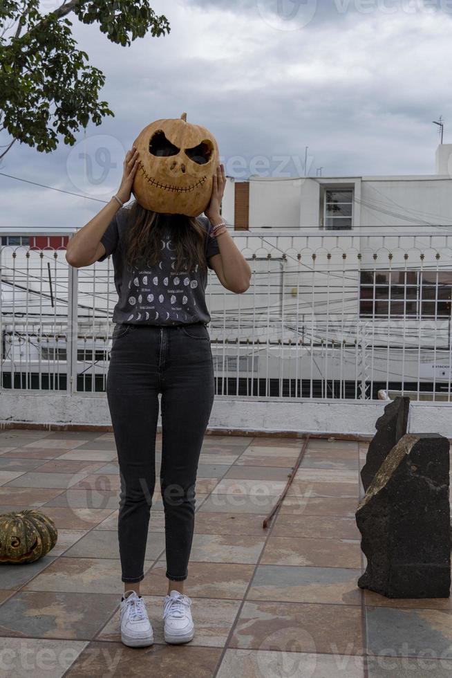 mujer joven con una calabaza en la cabeza para halloween, día de los muertos, méxico foto