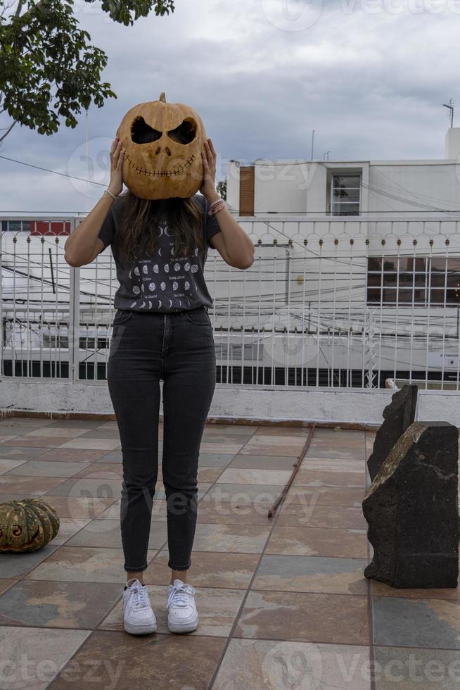 young woman with a pumpkin on her head for halloween, day of the dead, mexico photo