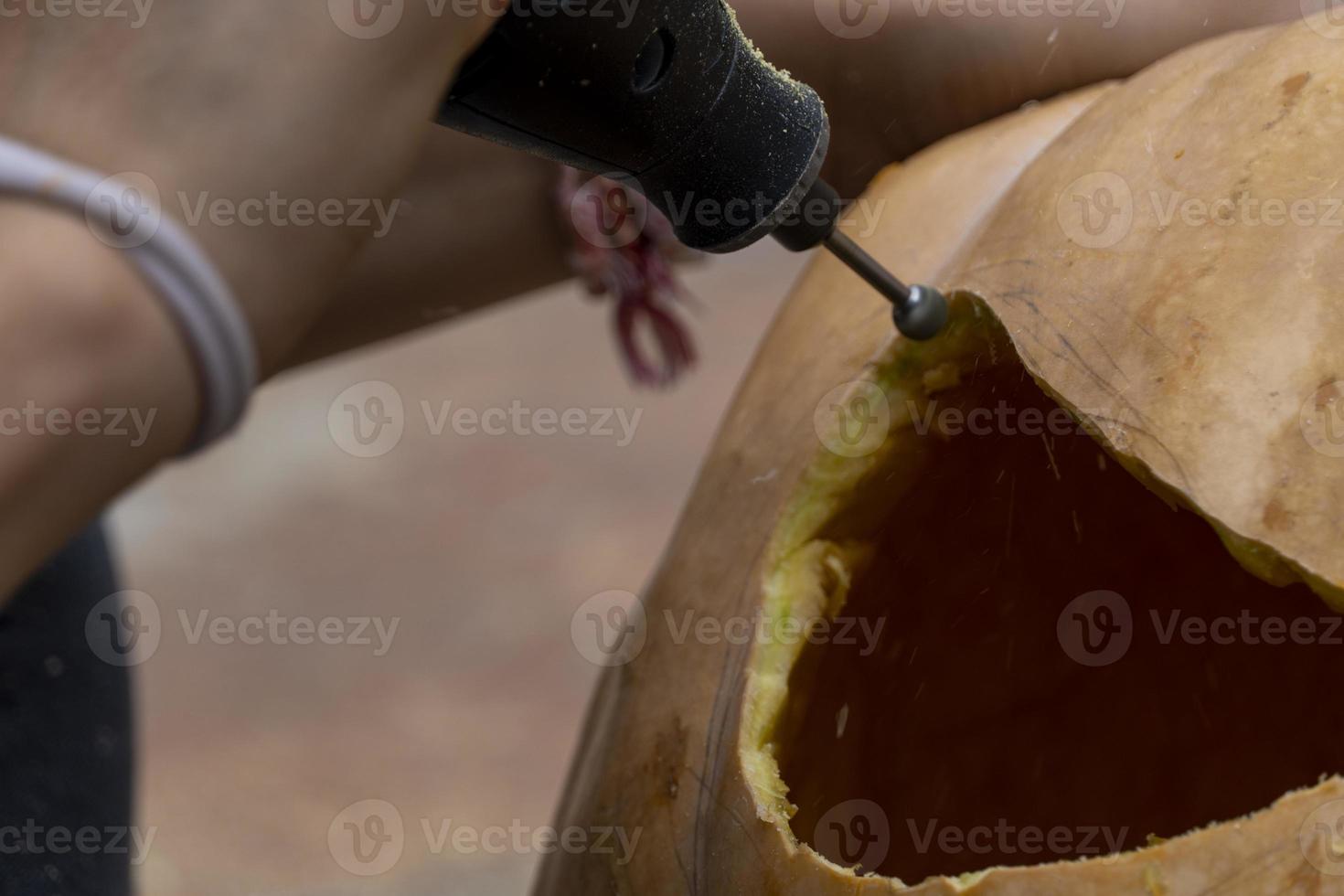 young man with a drill or dremel drilling a pumpkin for halloween photo