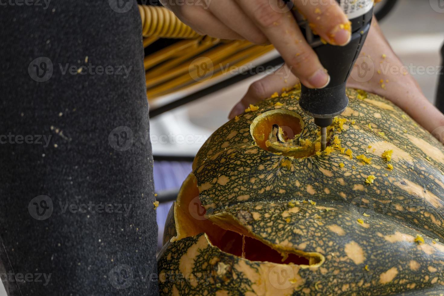 young man with a drill or dremel drilling a pumpkin for halloween photo