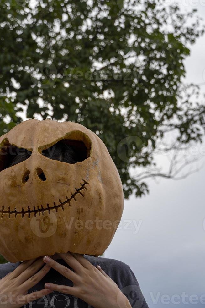 young woman with pumpkin head after cutting it off and putting a face on it, halloween, photo