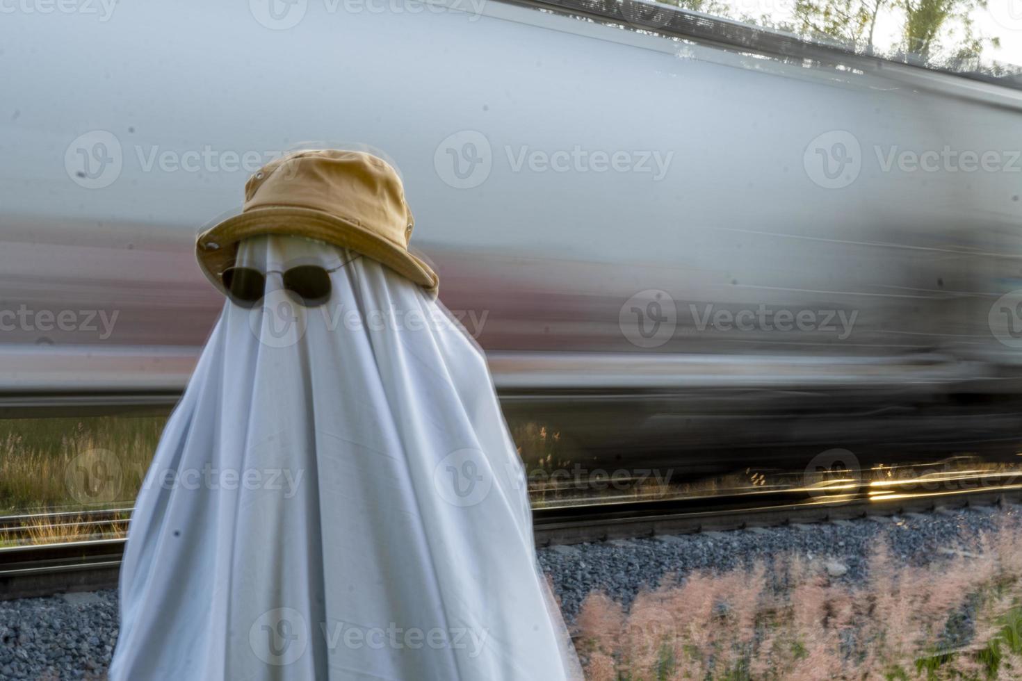 fantasma en el campo disfrutando del sol y el tren que pasa detrás, vías del tren foto