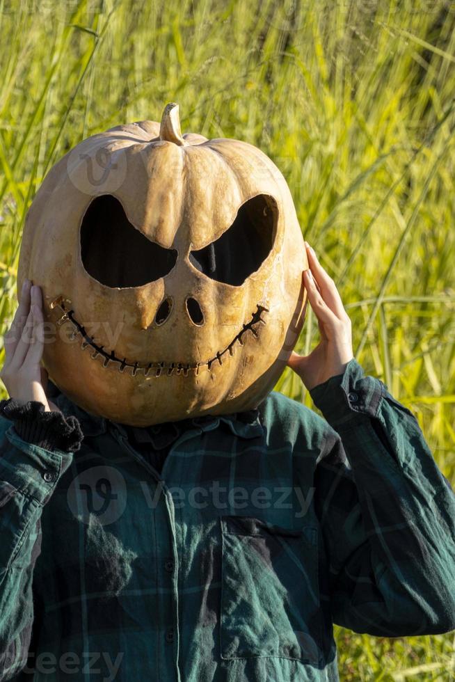 young woman with pumpkin head after cutting it off and putting a face on it, halloween, photo