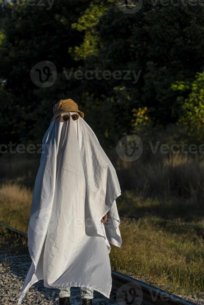 ghost in the countryside enjoying the sun and the train passing behind, train tracks photo