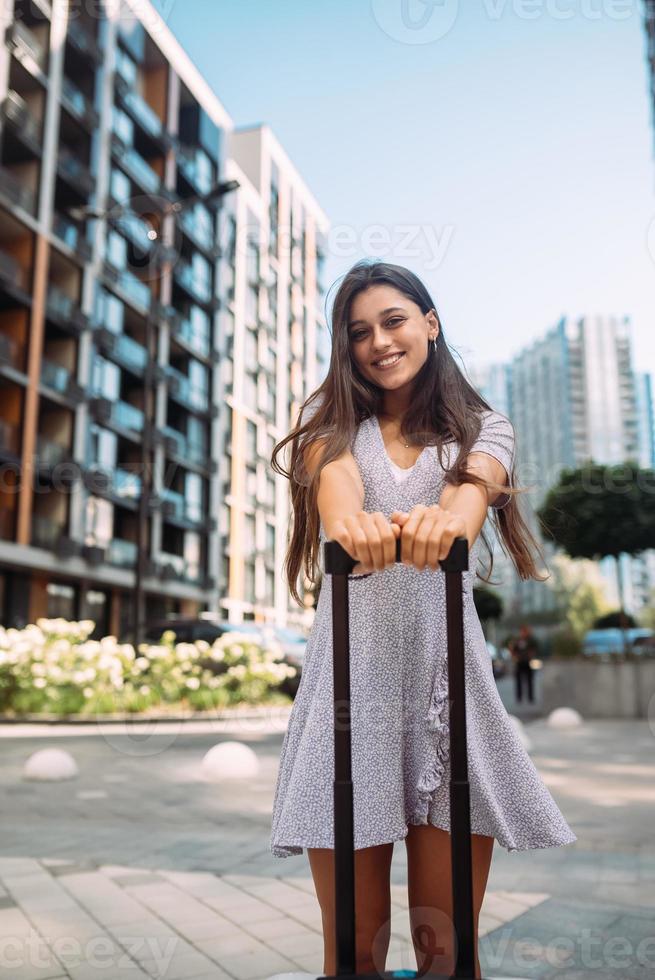 mujer elegante con maleta mirando a la cámara foto