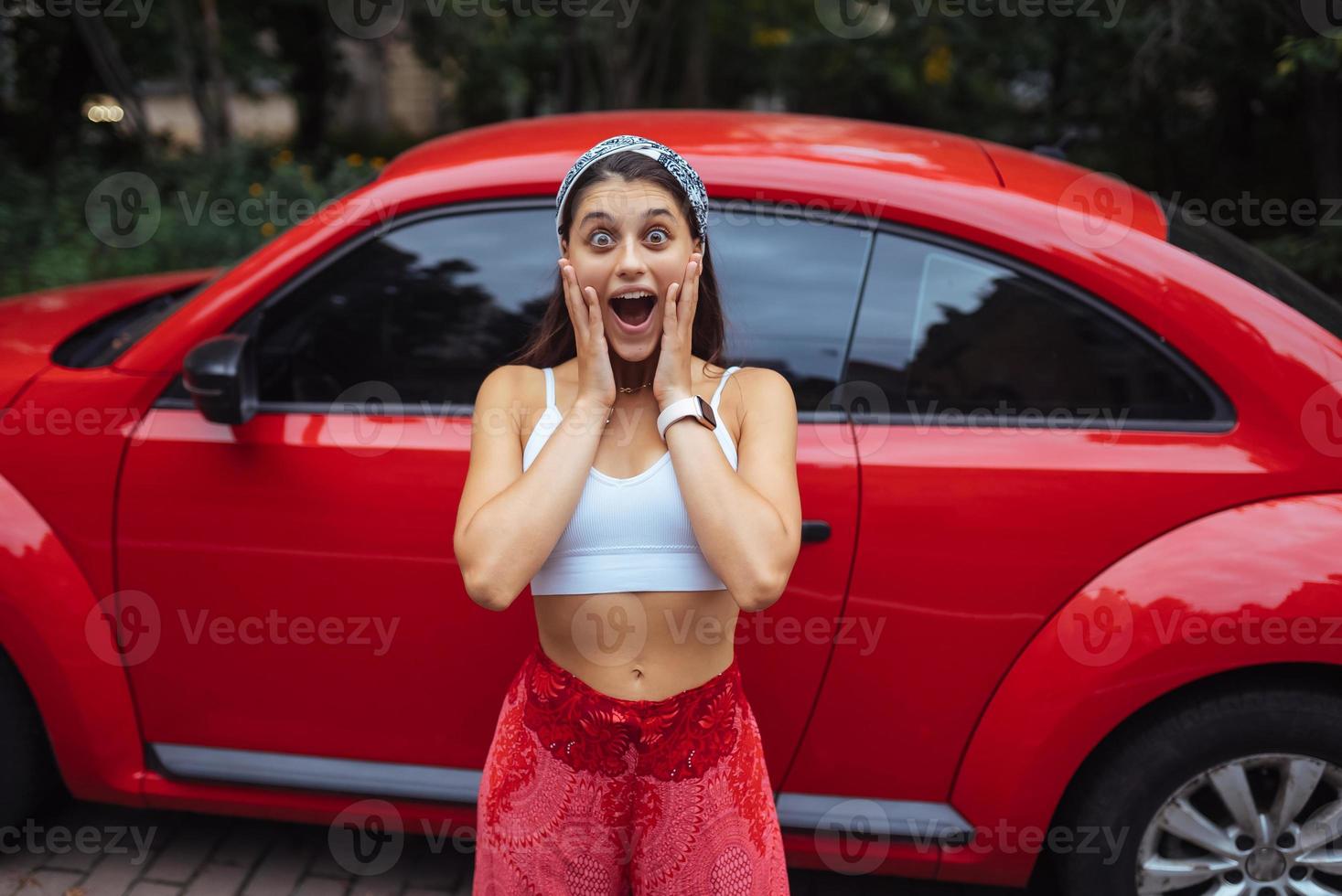 retrato de una mujer bastante caucásica parada contra un auto rojo nuevo foto