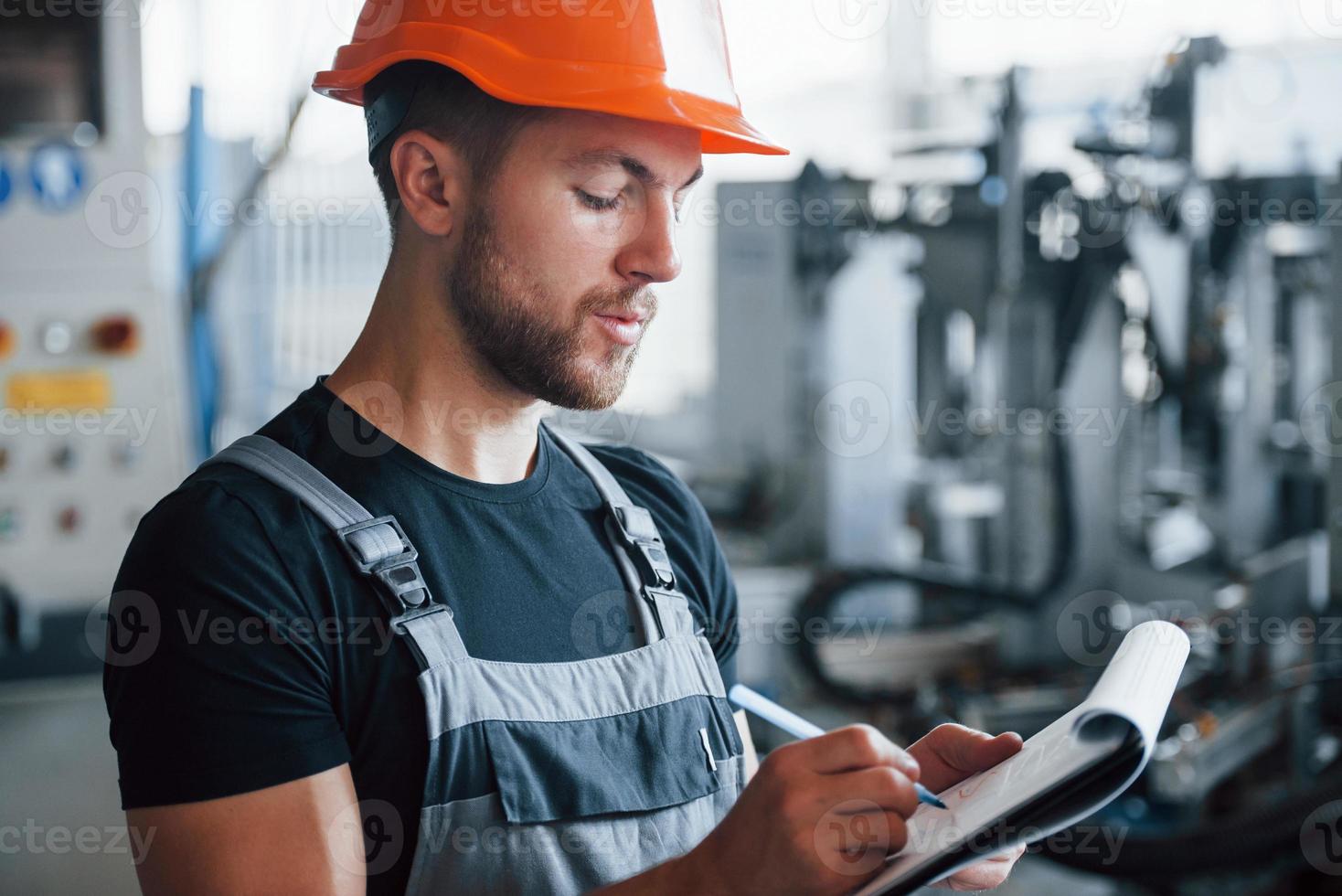 Industrial worker indoors in factory. Young technician with orange hard hat photo