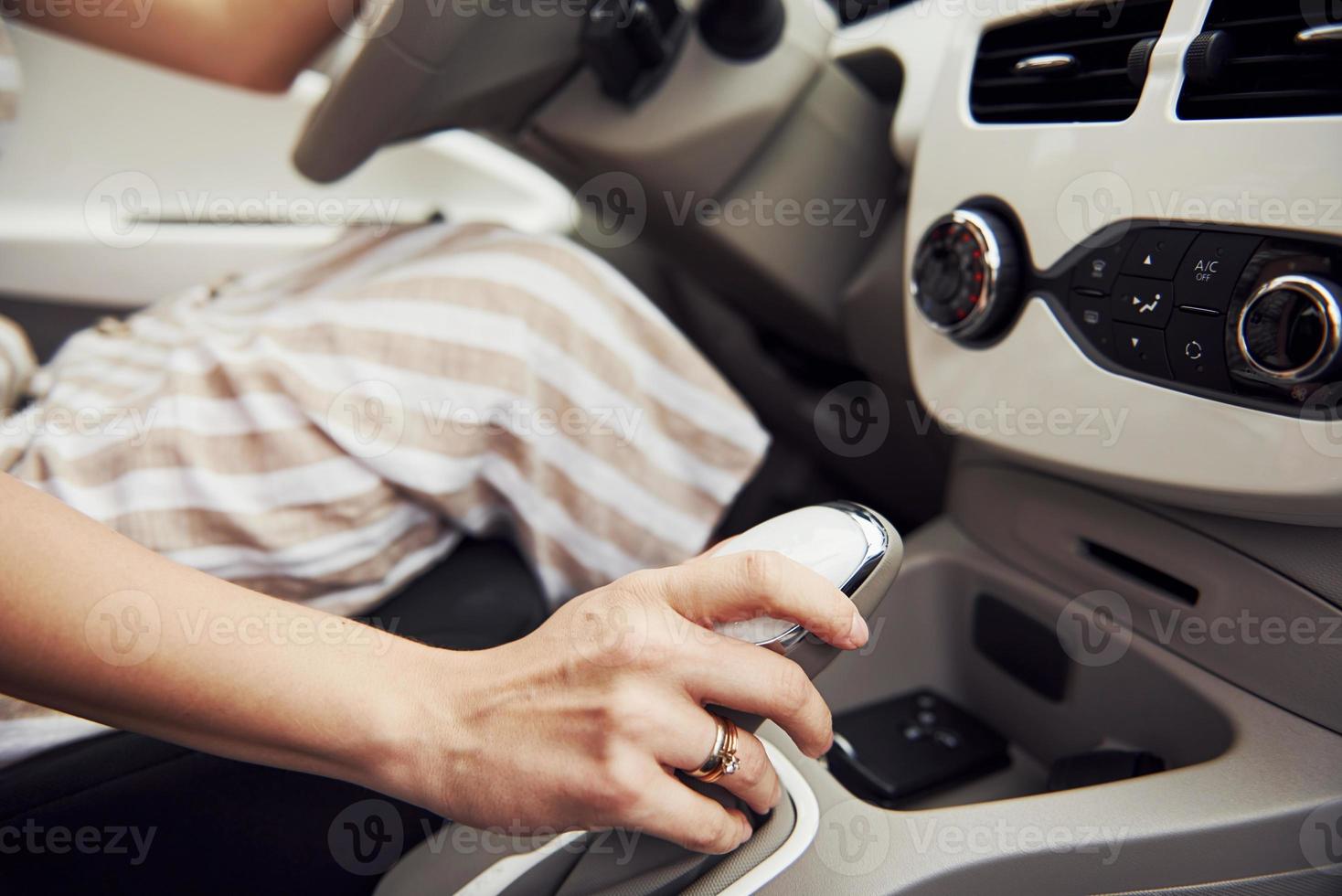 Close up view of woman's hand on gear stick in modern automobile with white interior photo