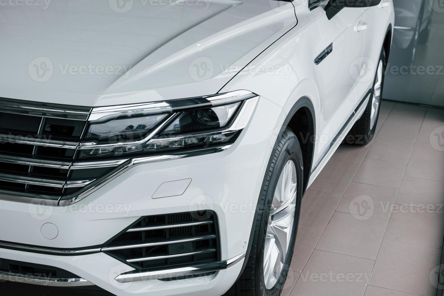 Clean headlights. Particle view of modern luxury white car parked indoors at daytime photo