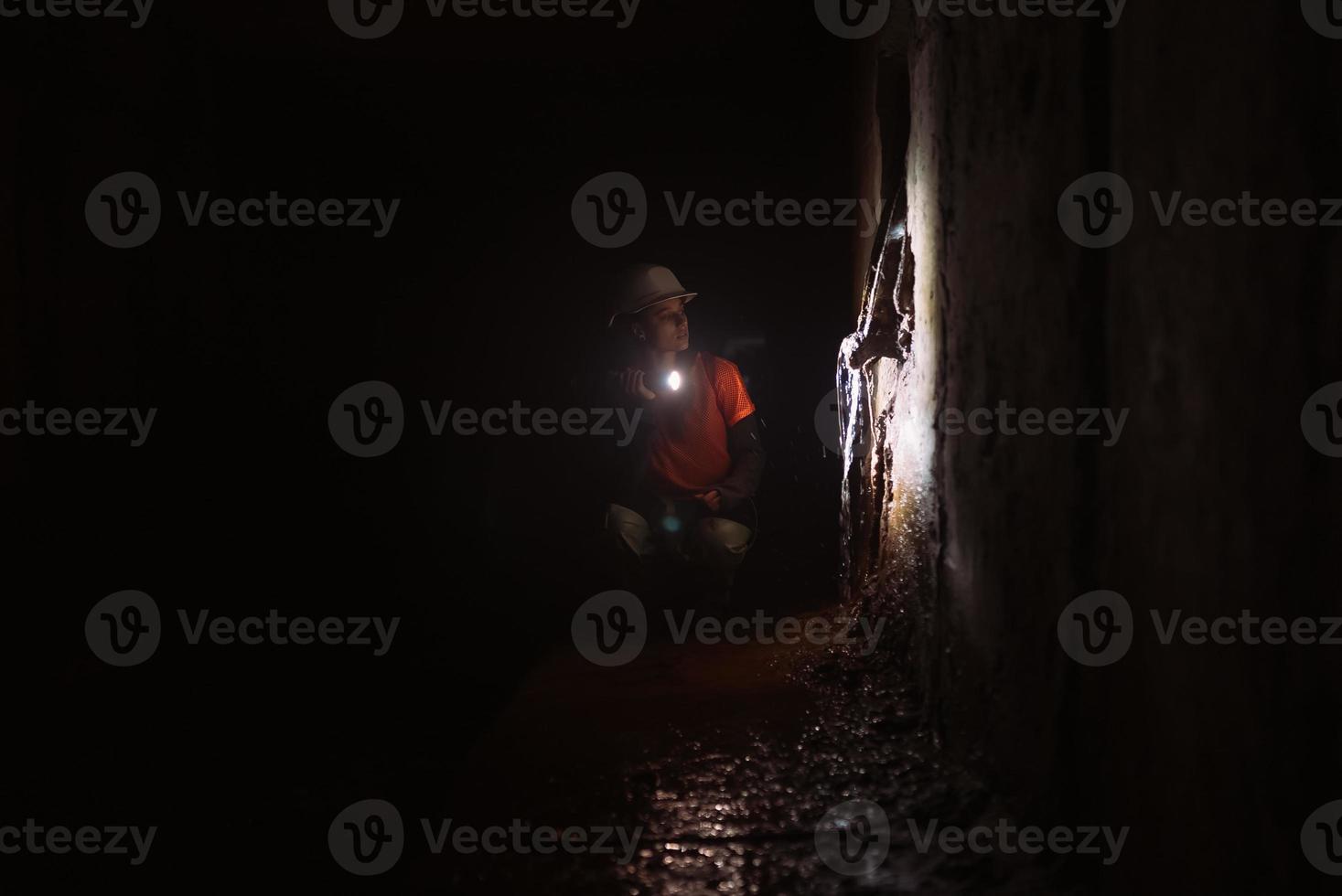 Female digger with flashlight explores the tunnel photo