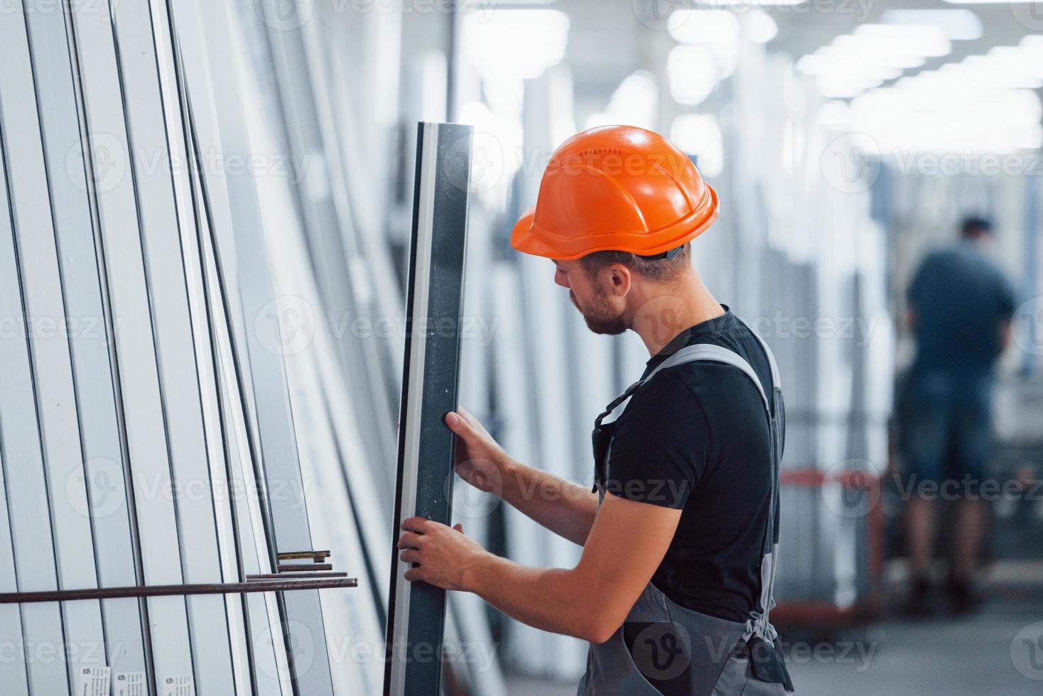 en el almacenamiento con muchos de los objetos. trabajador industrial en el interior de la fábrica. joven técnico con casco naranja foto