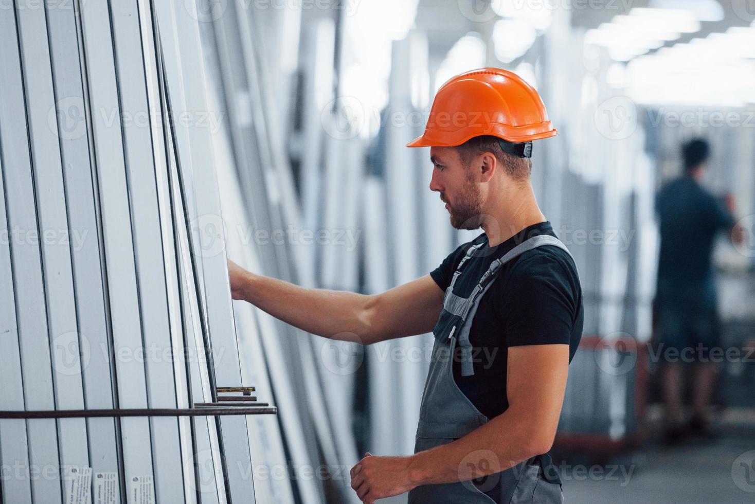 en el almacenamiento con muchos de los objetos. trabajador industrial en el interior de la fábrica. joven técnico con casco naranja foto