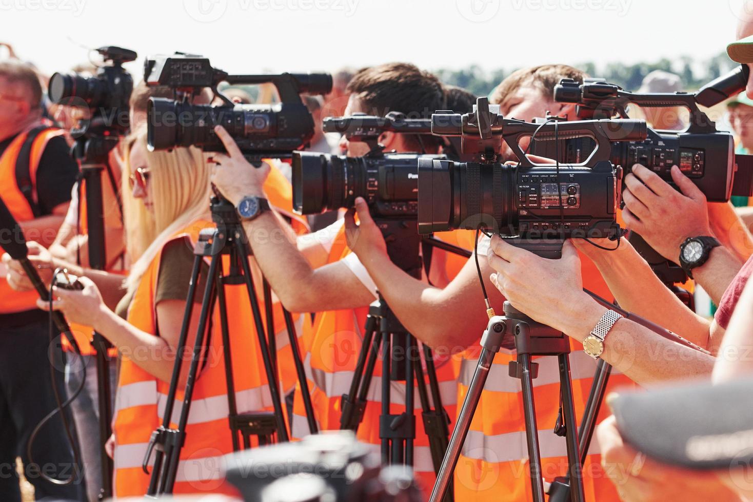 Group of people in yellow uniform and with cameras stands outdoors on the field photo
