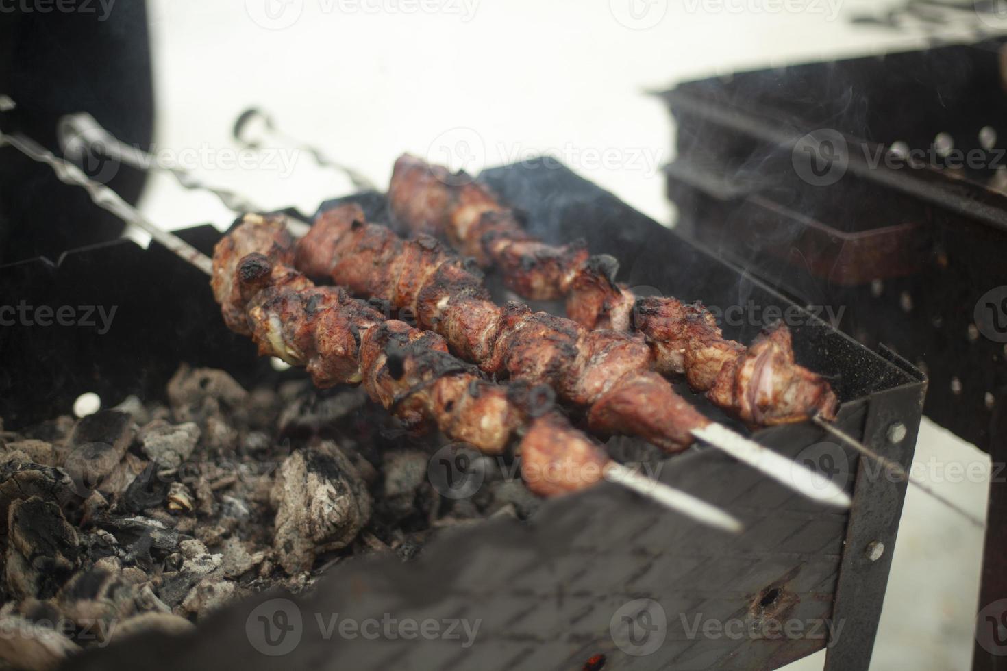 Meat is fried outside. Raw meat planted on blades. Heating food on coals. photo