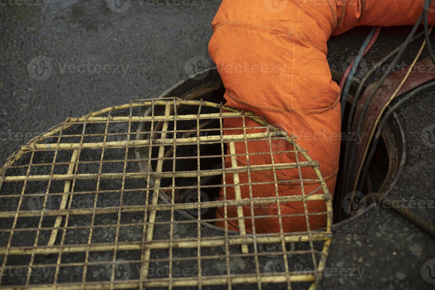 tubo naranja desciende en la escotilla. reparación de alcantarillado. bombeo de aguas residuales. suministro de aire. foto