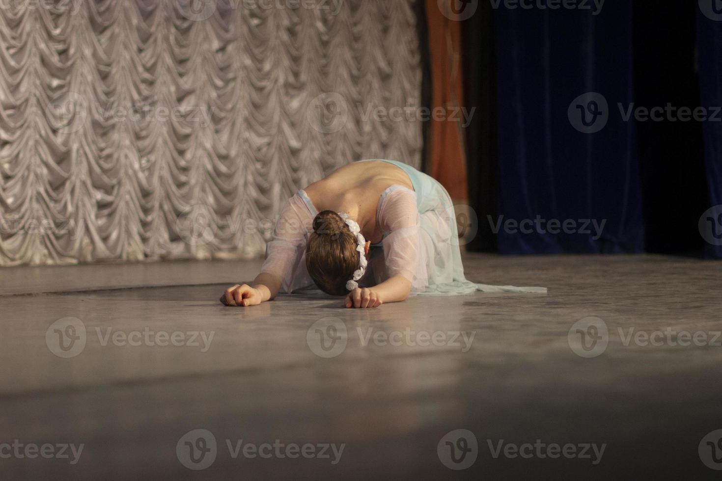 The girl lies on the stage. The ballerina performs. Beautiful movements of the dancer. photo