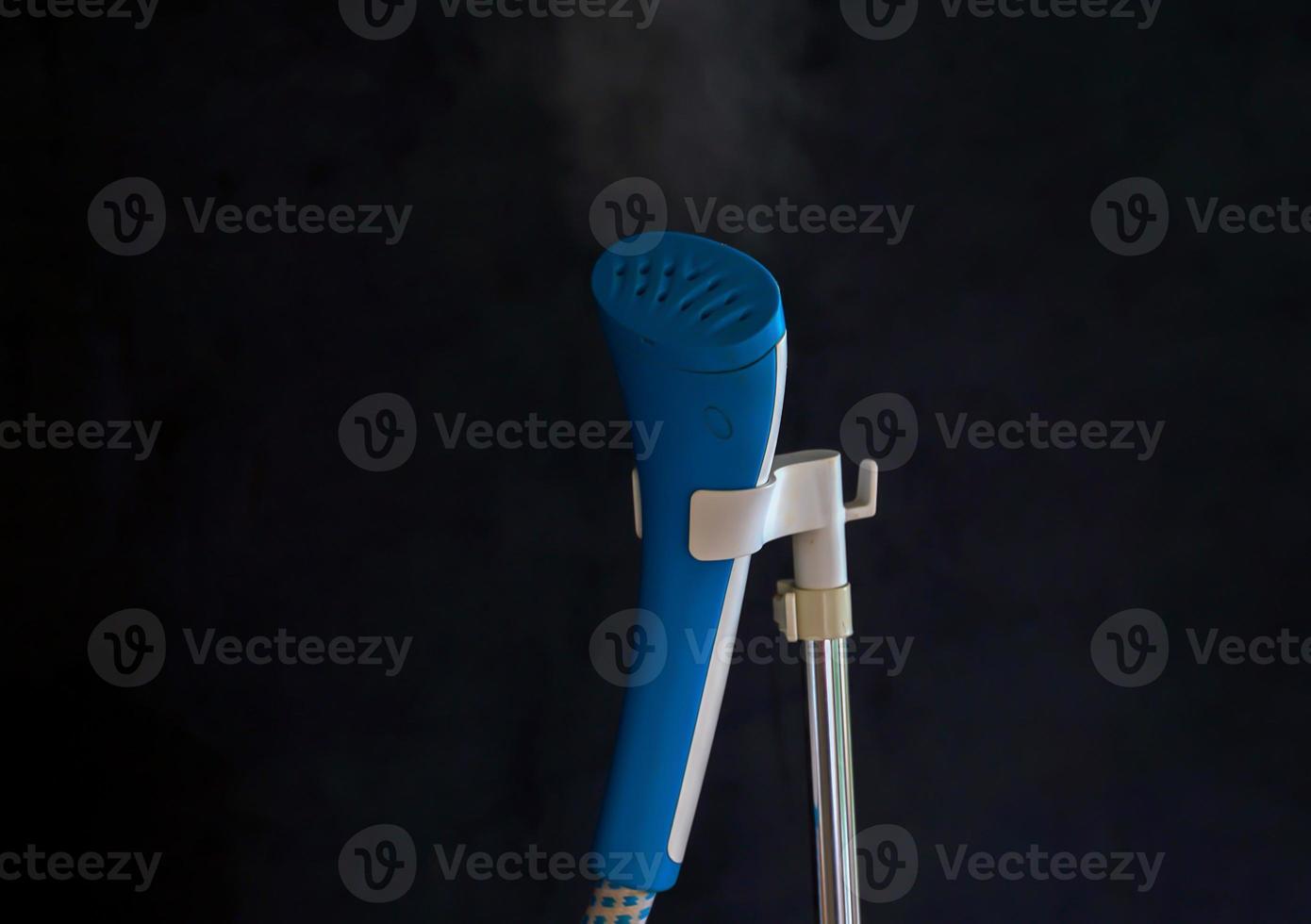 Blue Standing Steam Iron on a black background Save time in ironing and preserving clothes. Soft and selective focus. photo
