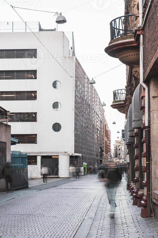 transeúntes y visitantes caminando por la calle del centro entre tiendas y pisos en el centro de amsterdam foto