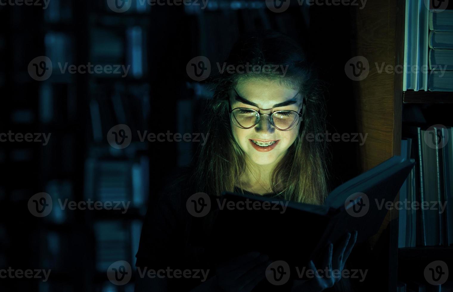 misteriosa luz verde proviene del libro. concepción de la creatividad. estudiante femenina está en la biblioteca. concepción de la educación foto