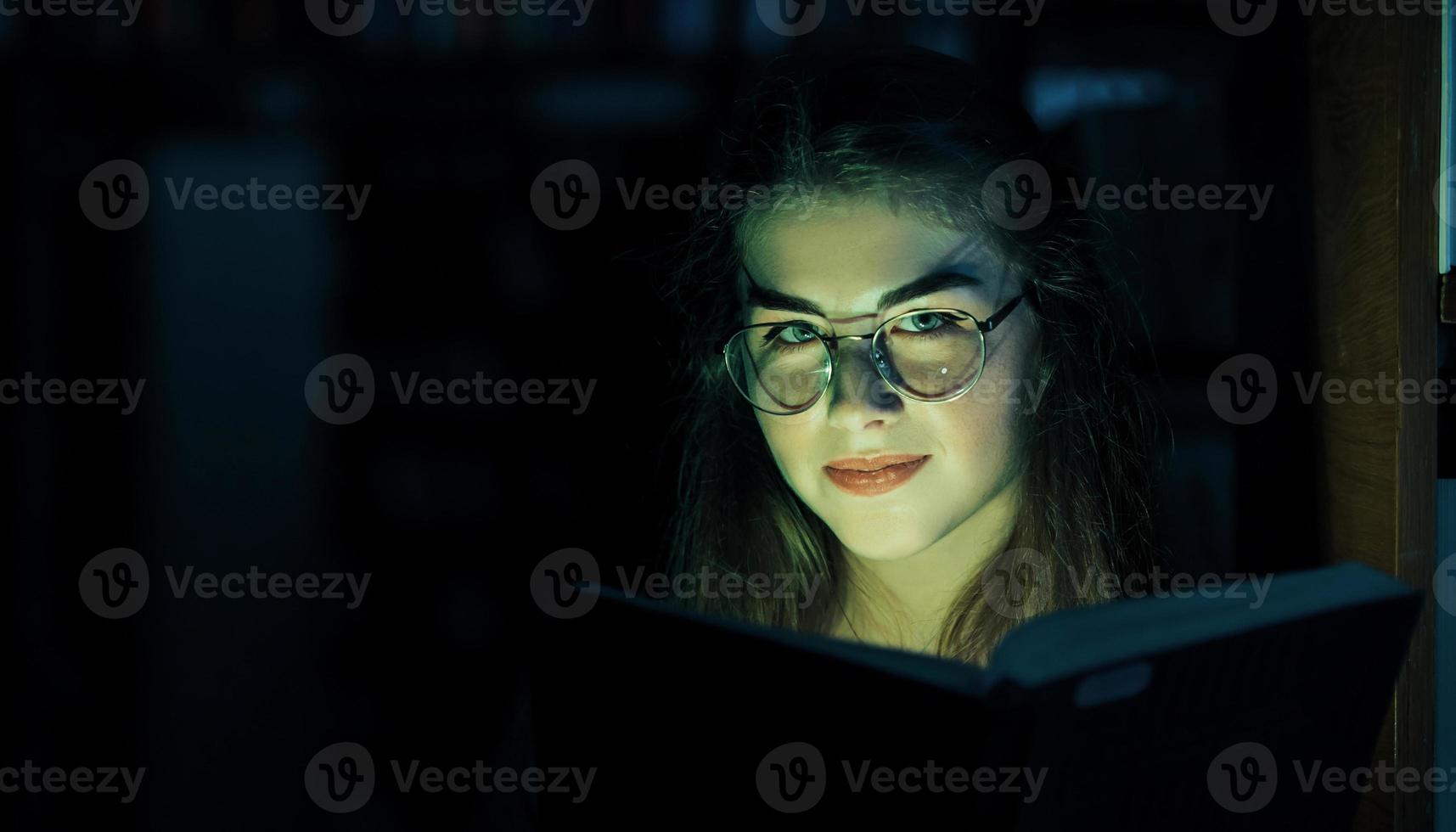 misteriosa luz verde proviene del libro. concepción de la creatividad. estudiante femenina está en la biblioteca. concepción de la educación foto