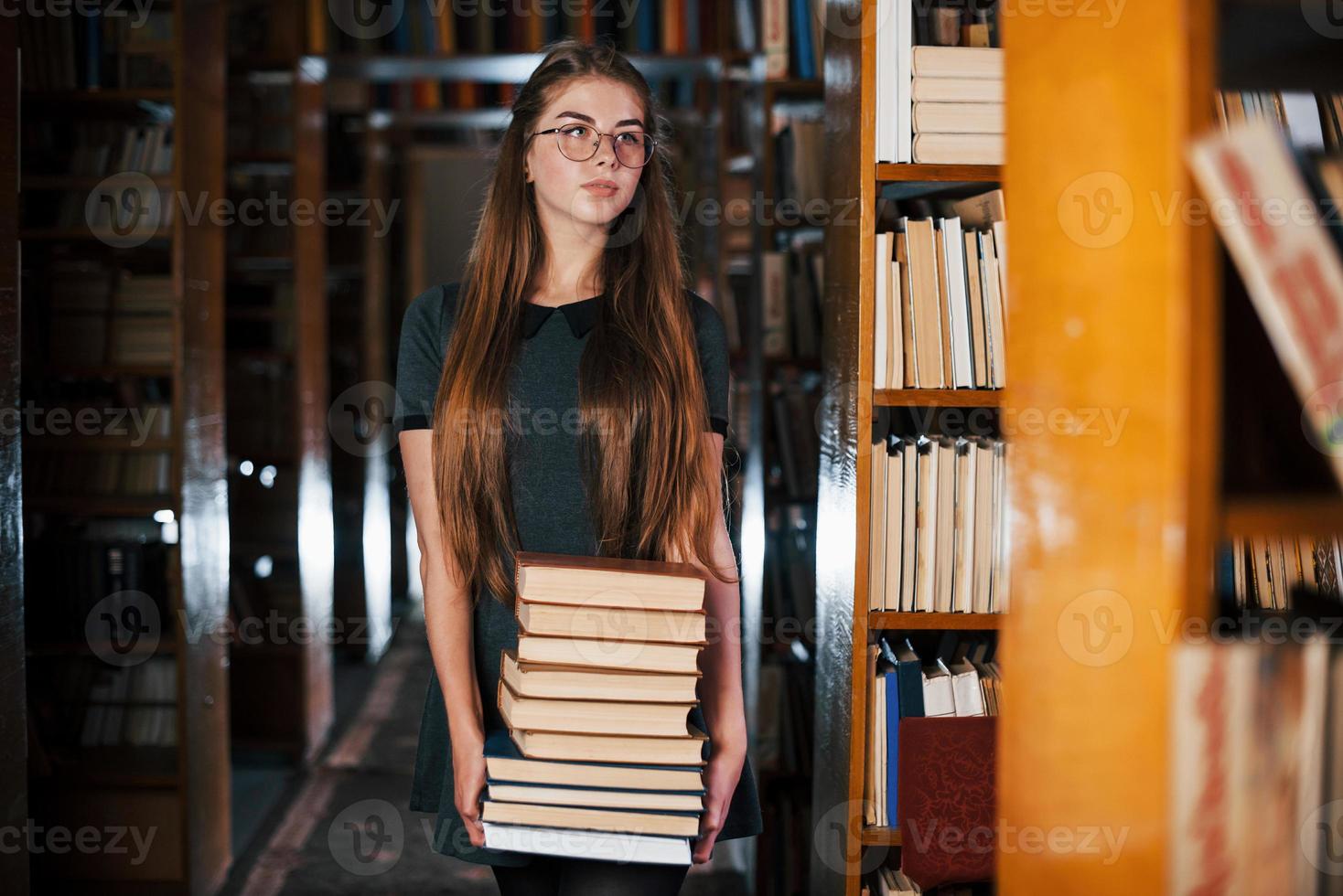 There is a lot of information in that books that in hands. Female student is in library. Conception of education photo