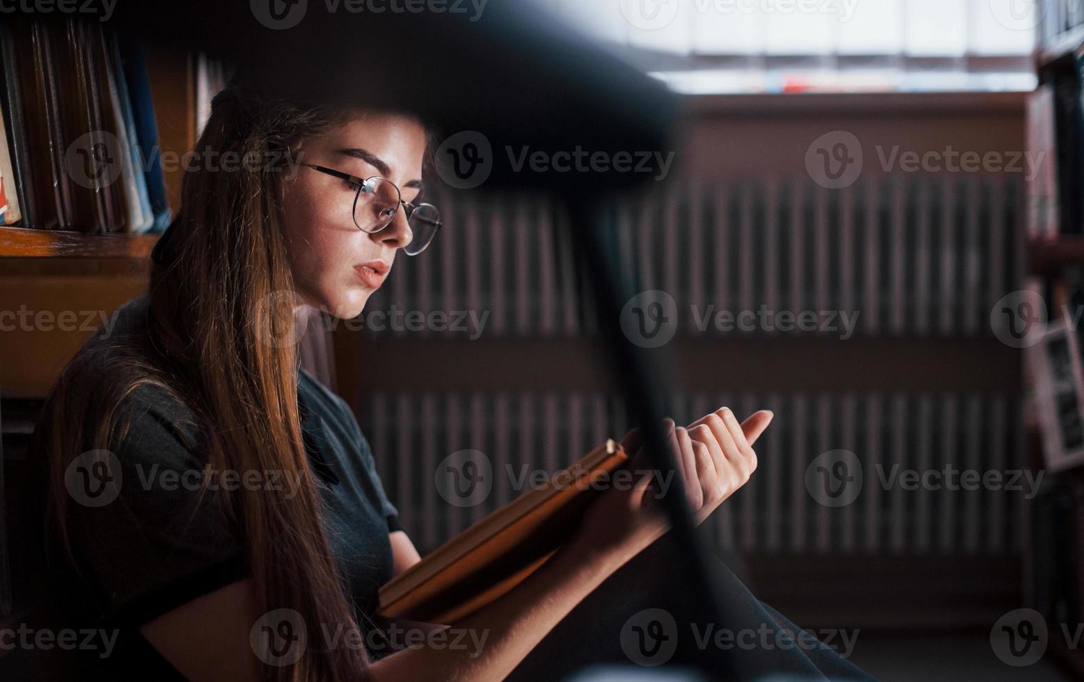Concentrated at reading. Female student is in library that full of books. Conception of education photo