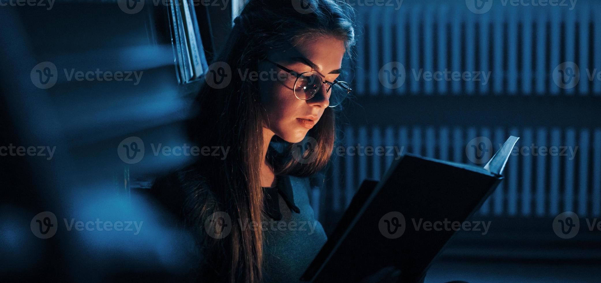 Getting smarter every day. Female student is in library that full of books. Conception of education photo