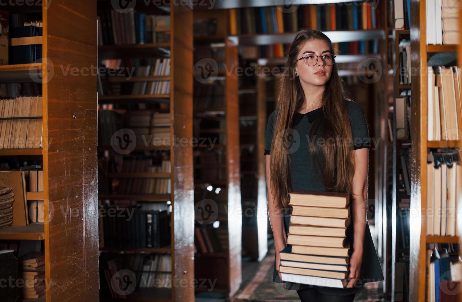 There is a lot of information in that books that in hands. Female student is in library. Conception of education photo