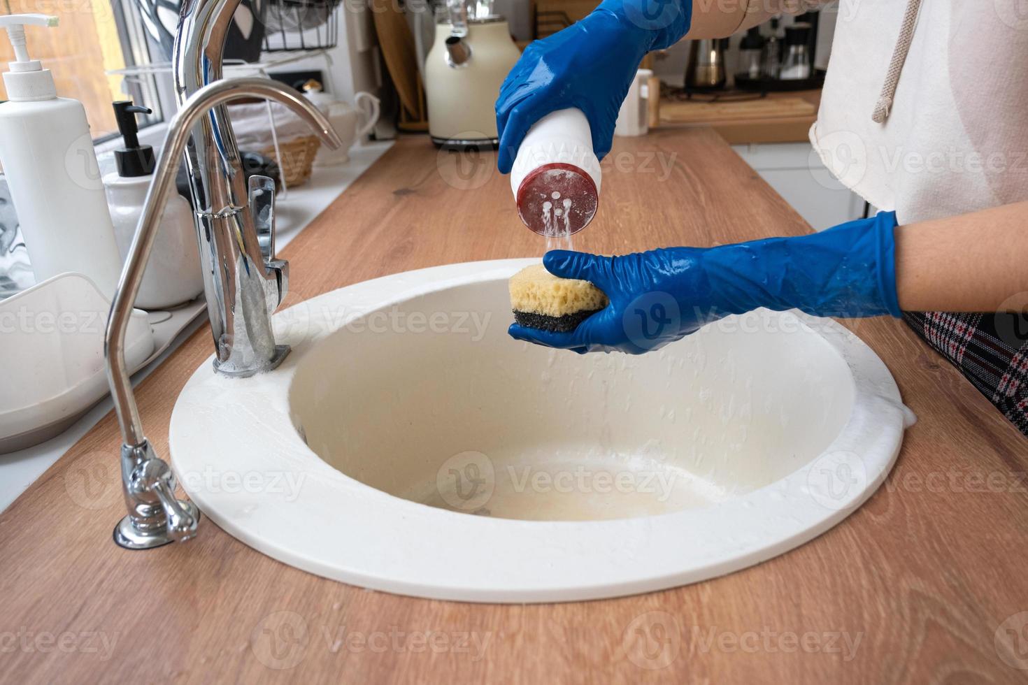Cleaning sink in kitchen, Hand in gloves and sponge, detergent, dry powder. cozy interior of the home, restoring order, cleanliness, disinfection photo
