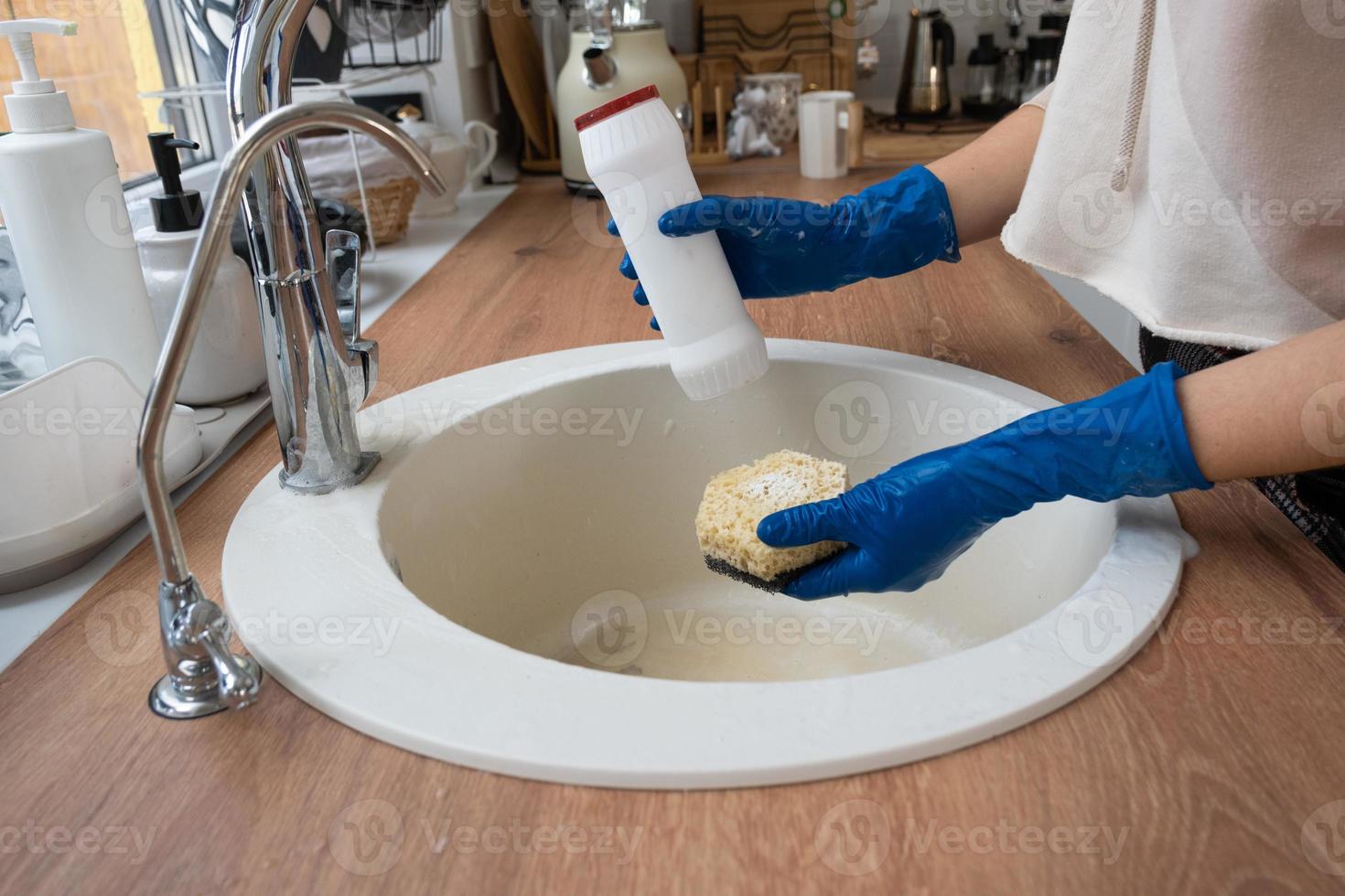 Cleaning sink in kitchen, Hand in gloves and sponge, detergent, dry powder. cozy interior of the home, restoring order, cleanliness, disinfection photo