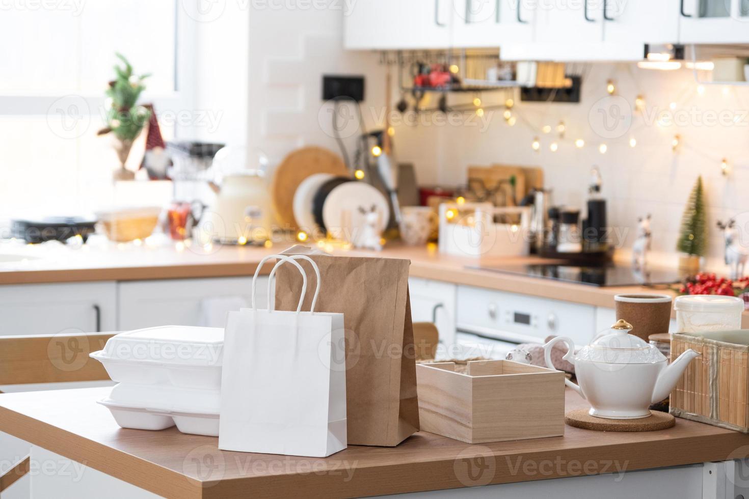 Food delivery service containers on table white scandi festive kitchen in christmas decor. Eve New year, saving time, too lazy to cook, hot order, disposable plastic box in fairy light. mock up photo