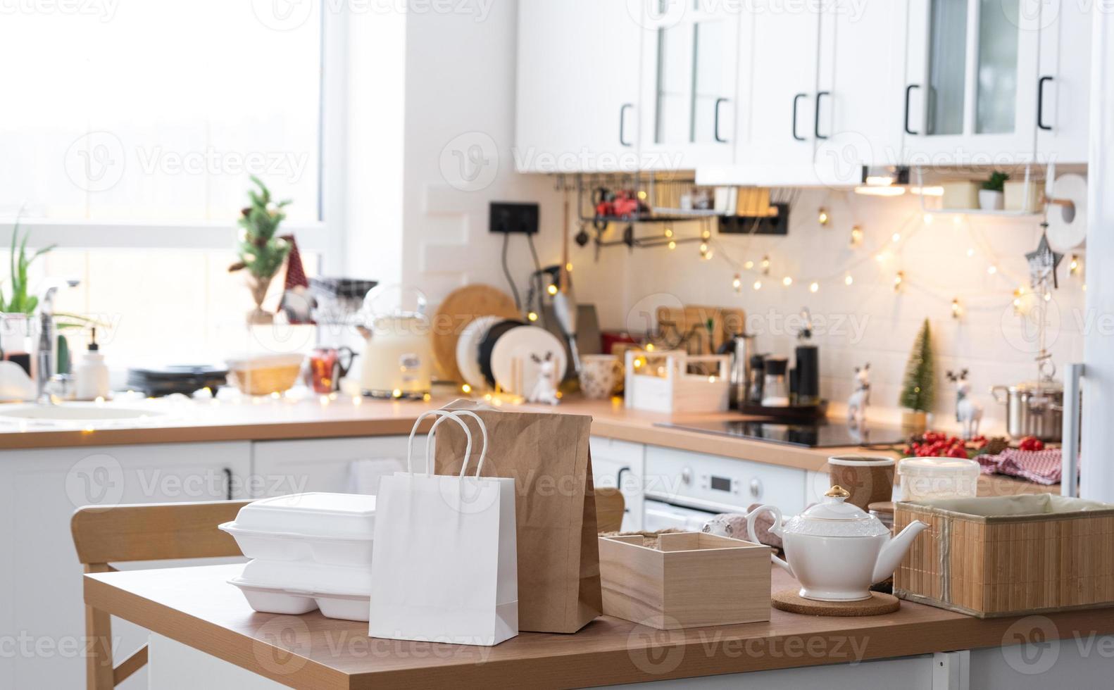 Food delivery service containers on table white scandi festive kitchen in christmas decor. Eve New year, saving time, too lazy to cook, hot order, disposable plastic box in fairy light. mock up photo